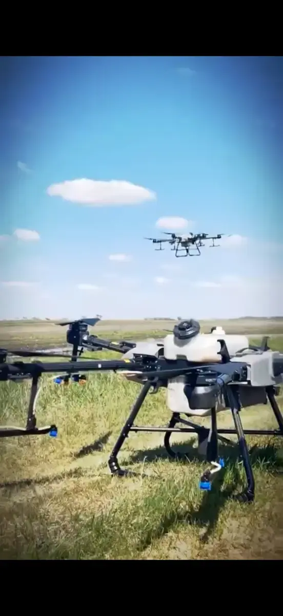 Two DJI Agras spray drones in the Pro Ag Solutions fleet staged in a field with a third drone airborne overhead